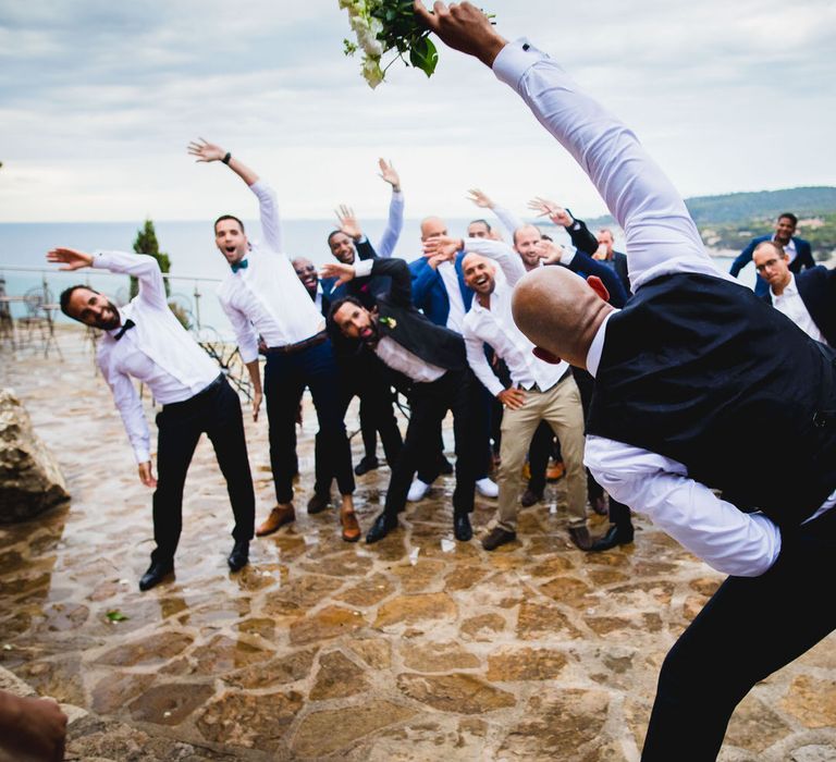 The groom getting ready to throw the bouquet into a crowd of male guests