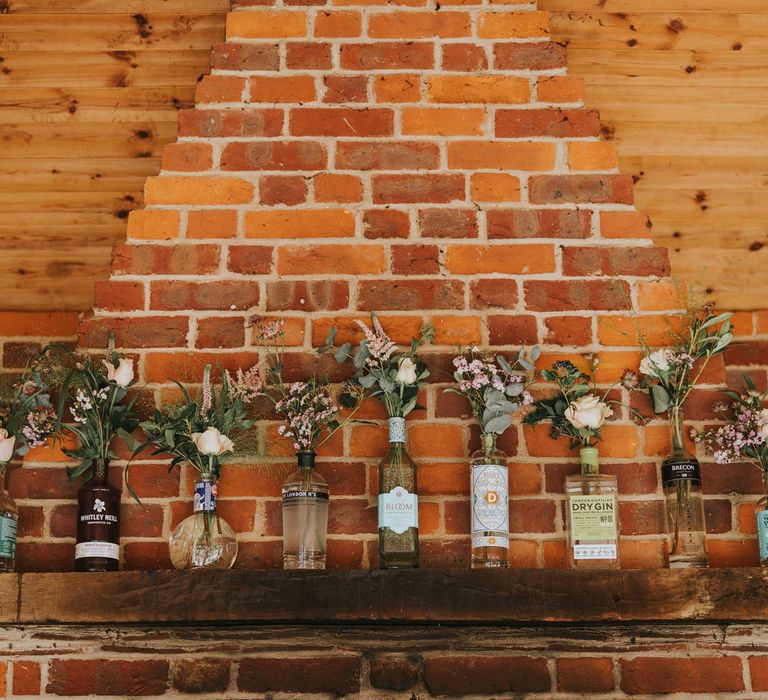 Gin bottles filled florals line brick wall