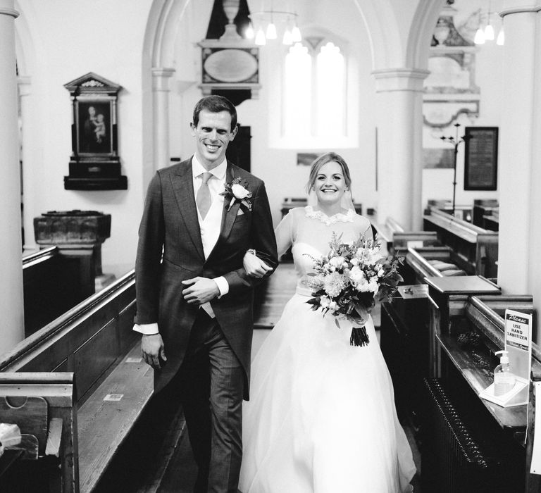 Black & white image of bride & groom leaving the church