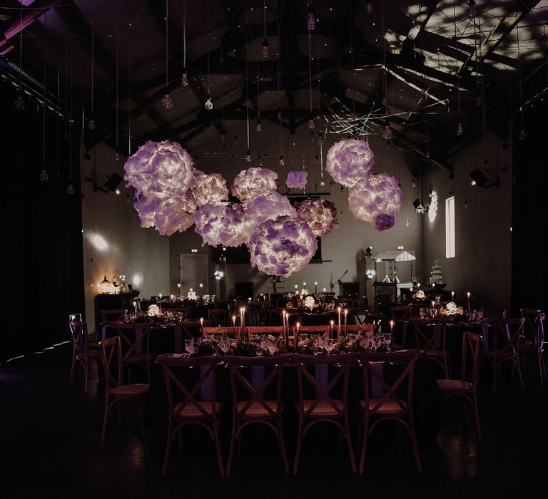 Dimly lit reception room, the tables are lit by candlelight and there is a purple light installation overhead