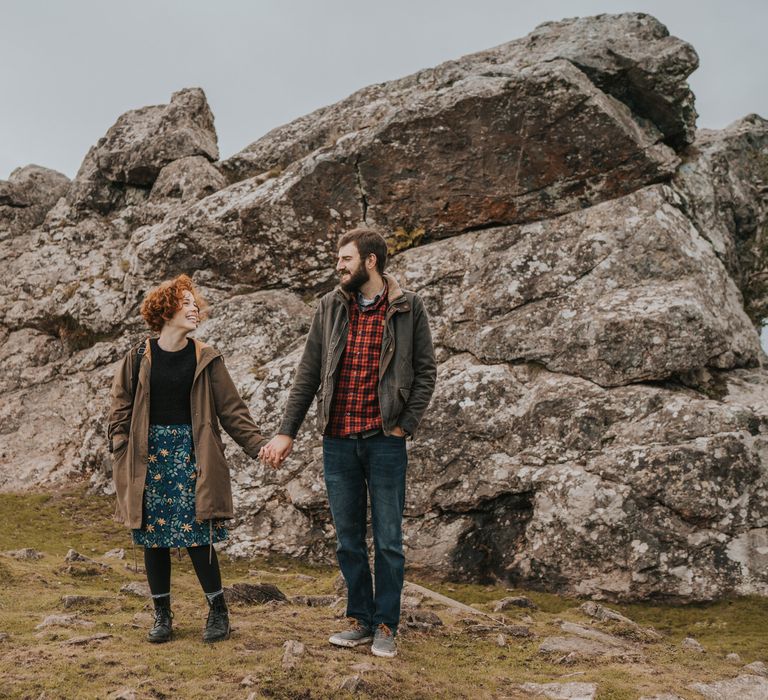 Couple walk together through Dartmouth countryside with rocks in the background