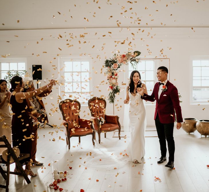 Bride and groom descending up the aisle with guests throwing confetti over them 