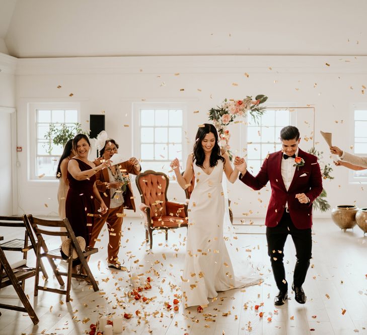 Bride and groom descending down the aisle at Core Clapton wedding ceremony with confetti thrown over them 