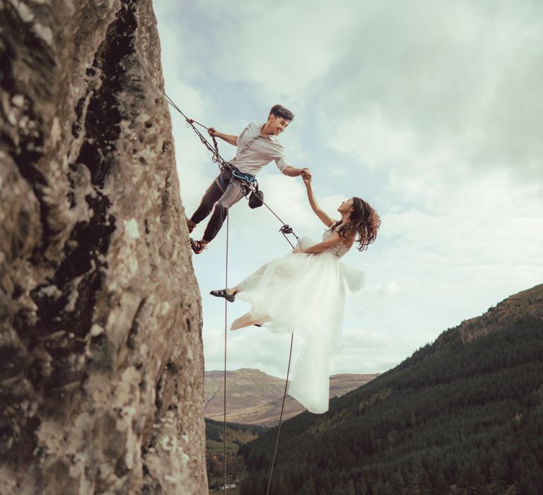 Couple rock climb on mountain in Scotland