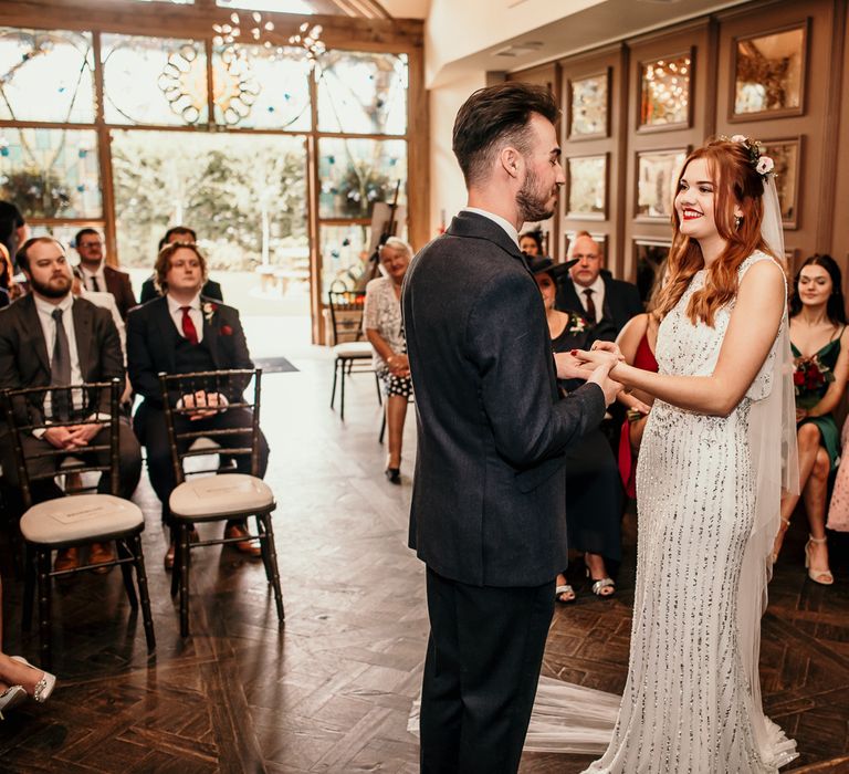 Bride & groom hold hands during wedding ceremony as wedding party watch