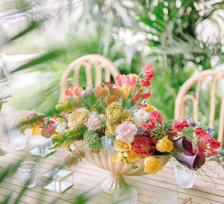 Colourful bouquet sits in shell shaped vase in the middle of wooden table