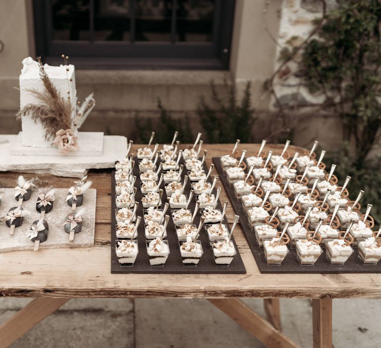 Dessert table with four-tier wedding cake, popsicles and individual desserts