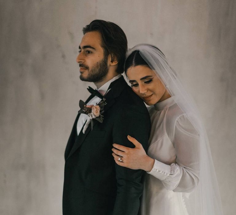 Bride holds the arms of groom and leans into him on their wedding day