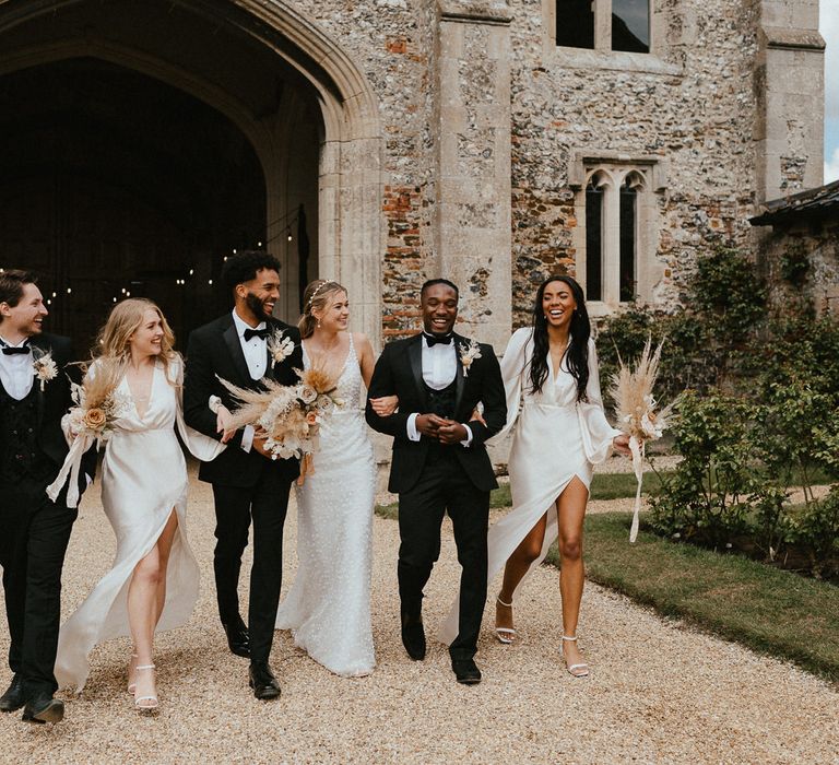 Stylish wedding party picture with groomsmen in tuxedos, bridesmaids in champagne satin dresses and the bride and appliqué gown 