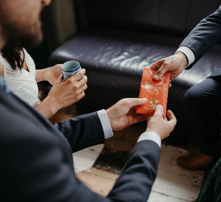 Father of the bride passing a red envelope to the newlyweds during their Chinese tea ceremony