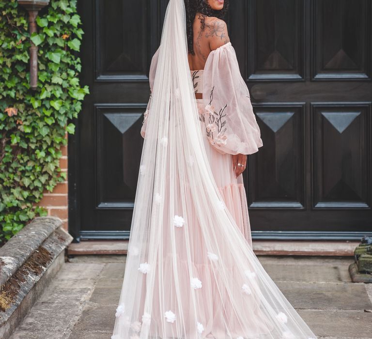 Black bride with long curly hair wearing a blush pink appliqué wedding veil 