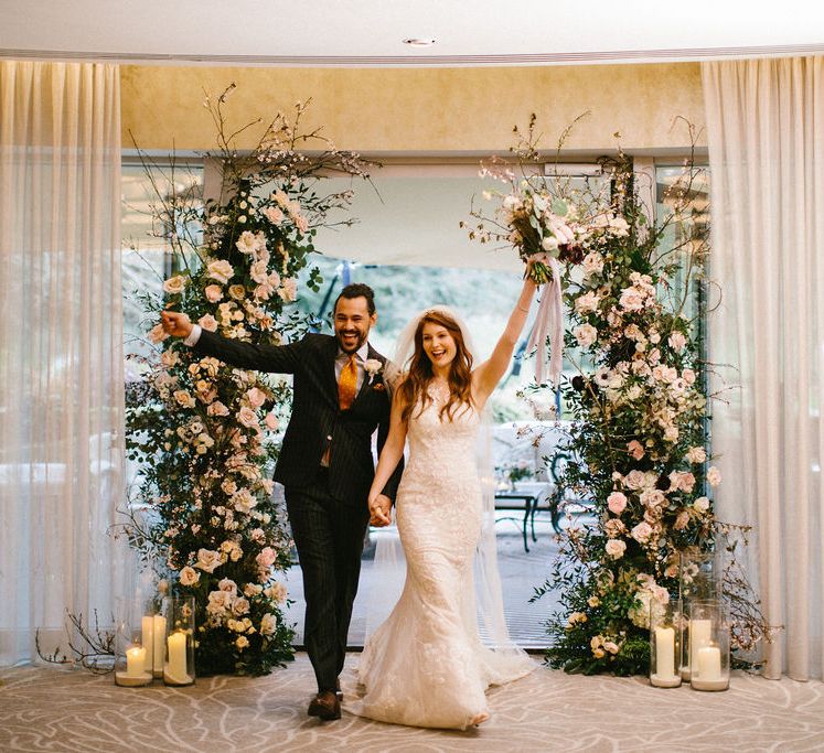 Classic bride in a lace Pronovias wedding dress entering the wedding reception with her groom decorated with floral arrangements and lanterns