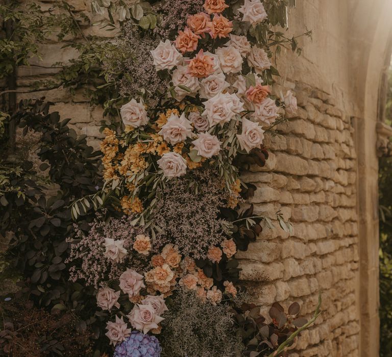 Pastel orange, coral, pink, and peach wedding flowers decorating the castle arch at Euridge Manor 