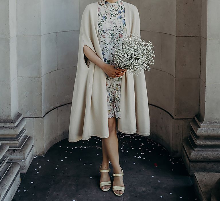 East Asian bride in a short blue floral wedding dress and beige coat cape holding a gypsophila wedding bouquet at Old Marylebone Town Hall 