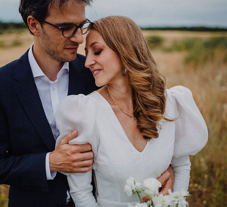 Bride leans her head into groom outdoors in golden fields for couples portraits