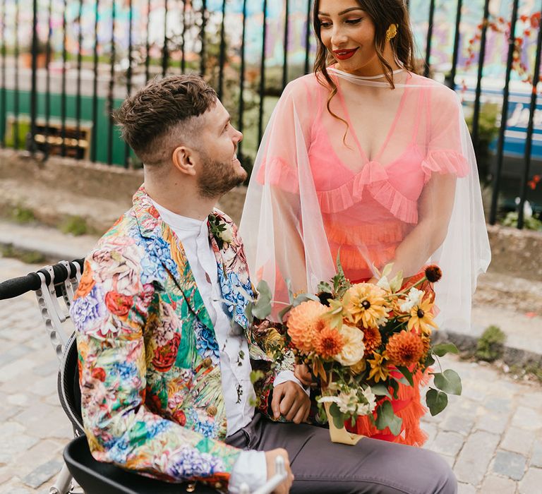 Interabled couple's colourful Shoreditch elopement with bride in a coral wedding dress and groom in a colourful patterned blazer 