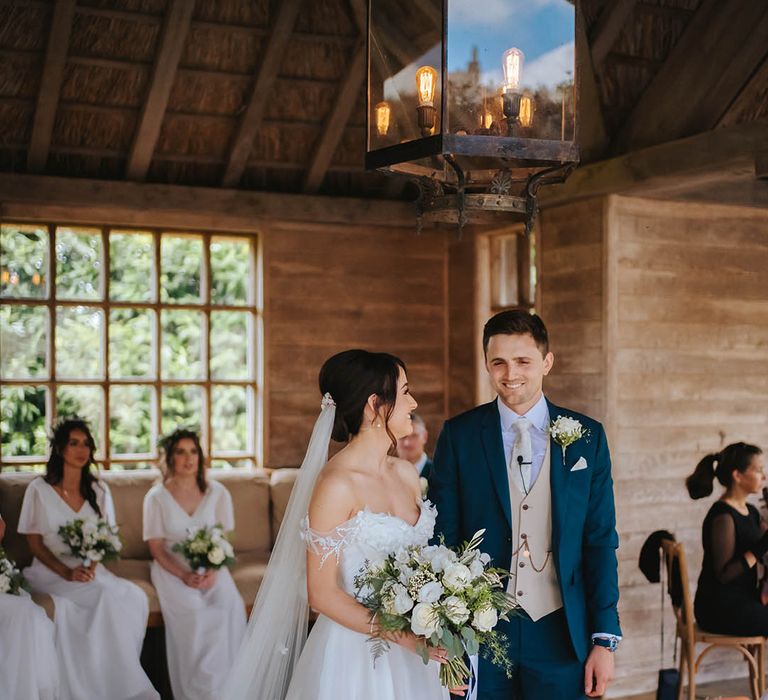 Bride & groom look lovingly at one another as wedding guests watch during ceremony