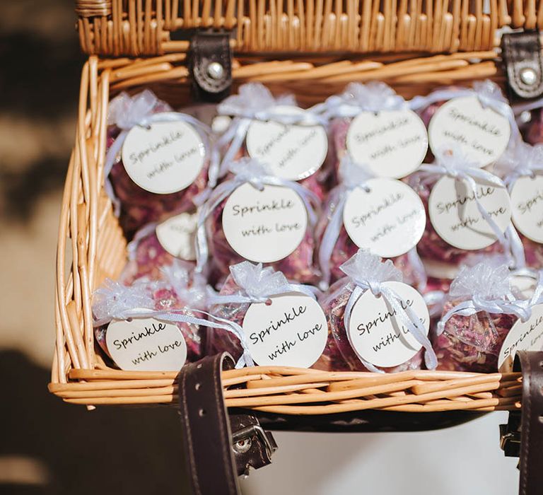 Confetti in satin bags tied with ribbon in wicker basket 