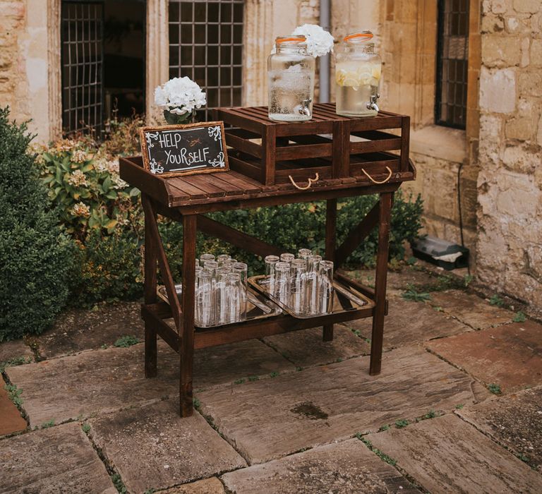 Wooden table and crates with drinks dispensers and glasses for outdoor wedding ceremony