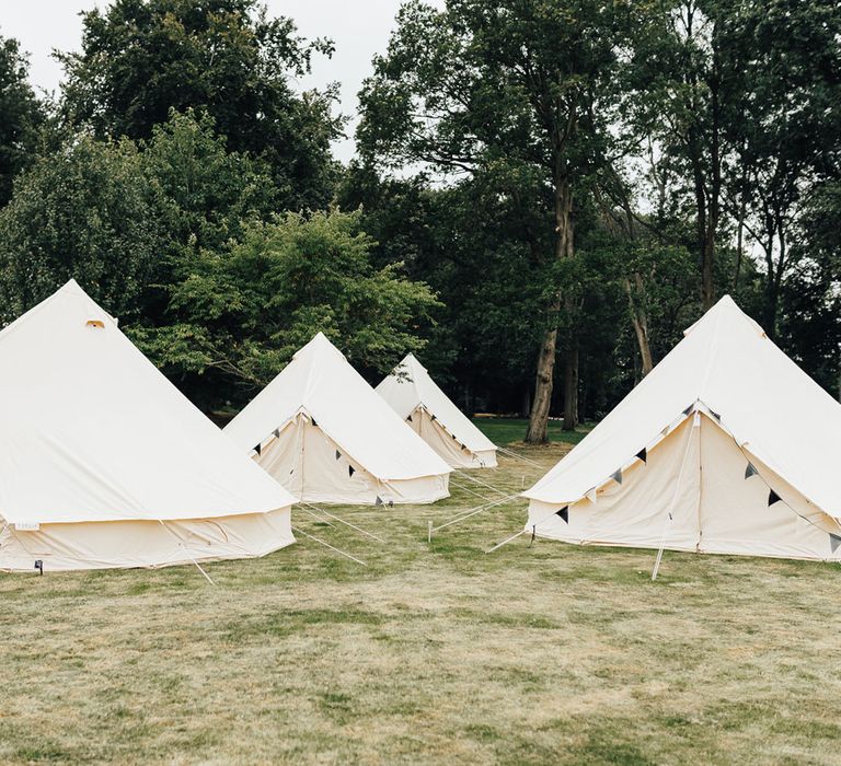 White bell top tents with bunting in field for sperry tent wedding