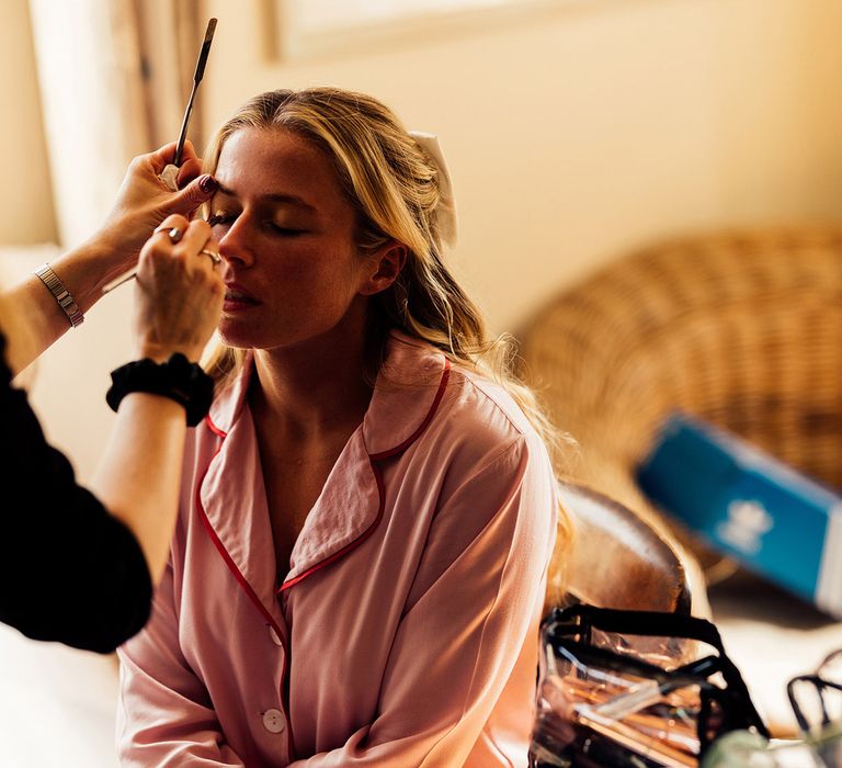 Bride in pink bridal pyjamas has her make up done before wedding in Hampshire