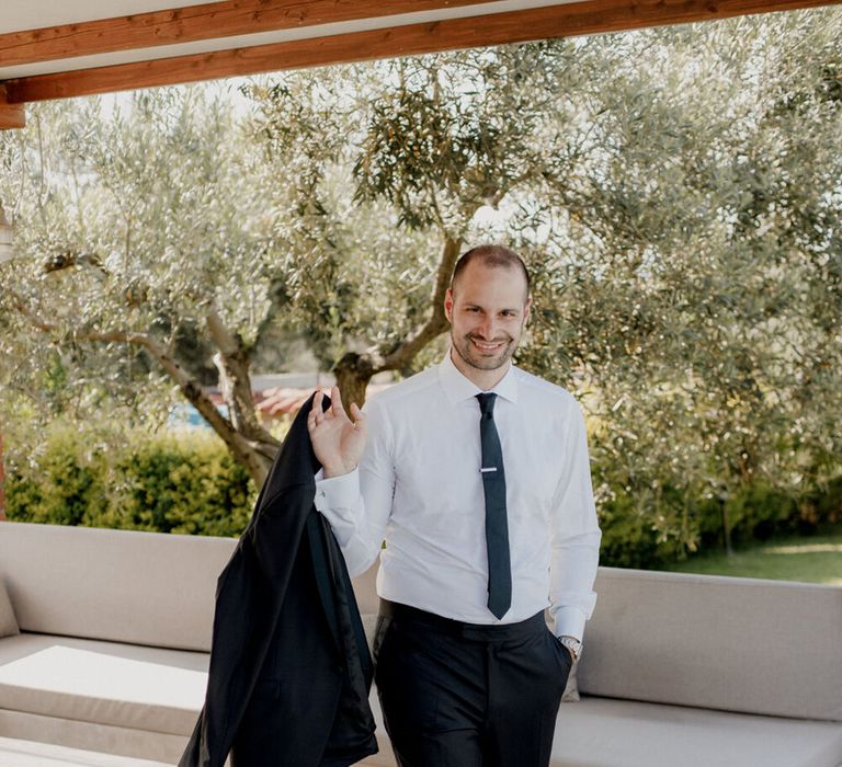 Groom walks with his suit jacket in hand 