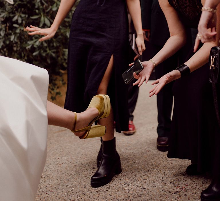 Guests fawn over the mustard yellow block platform heels worn by the bride