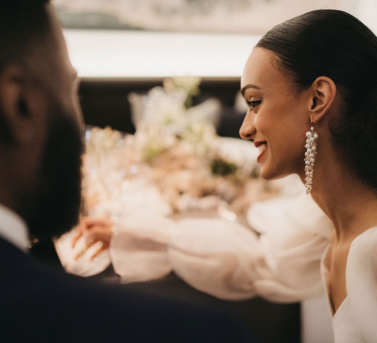 Black bride with central parting wedding hairstyle and pony tail wearing dangly pearl earrings 