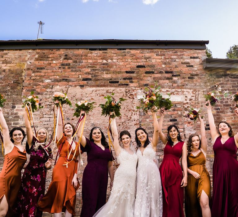 Purple, yellow, orange and red jewel tone bridesmaids dresses for autumnal theme lesbian wedding at Foxtail Barns wedding venue