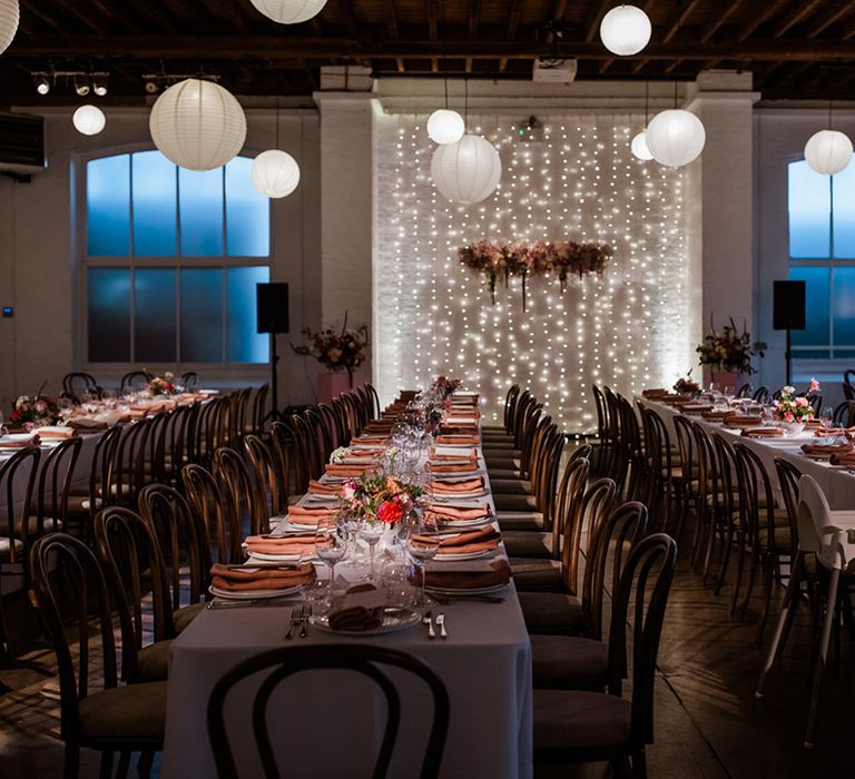 Pretty wedding reception with flower cloud, fairy lights, white paper lanterns with bright flowers and colourful napkins 