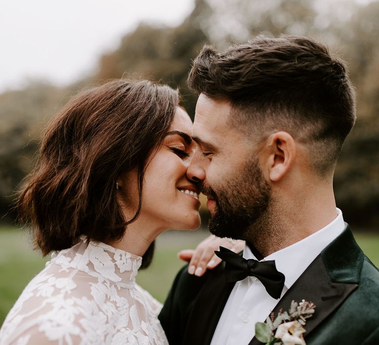 Bride and groom smile as they lean in for a kiss together