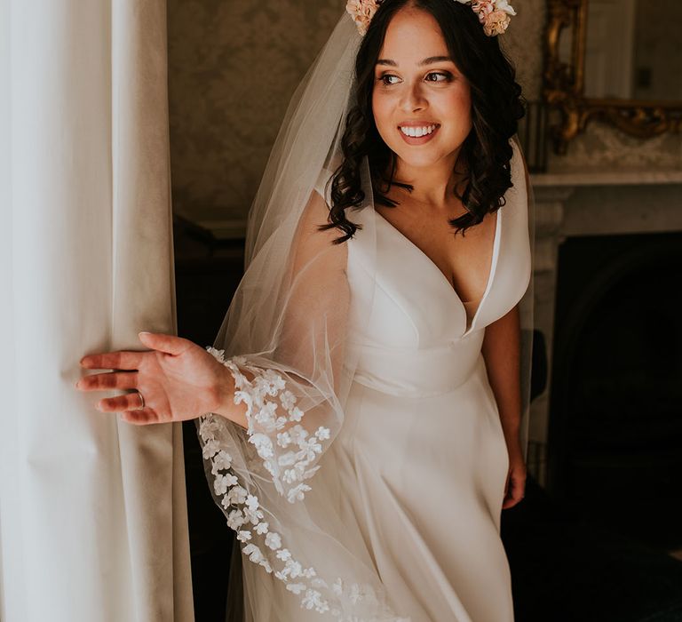 Bride in v-neck wedding dress with pink flower crown and Pronovias flower embroidered veil 