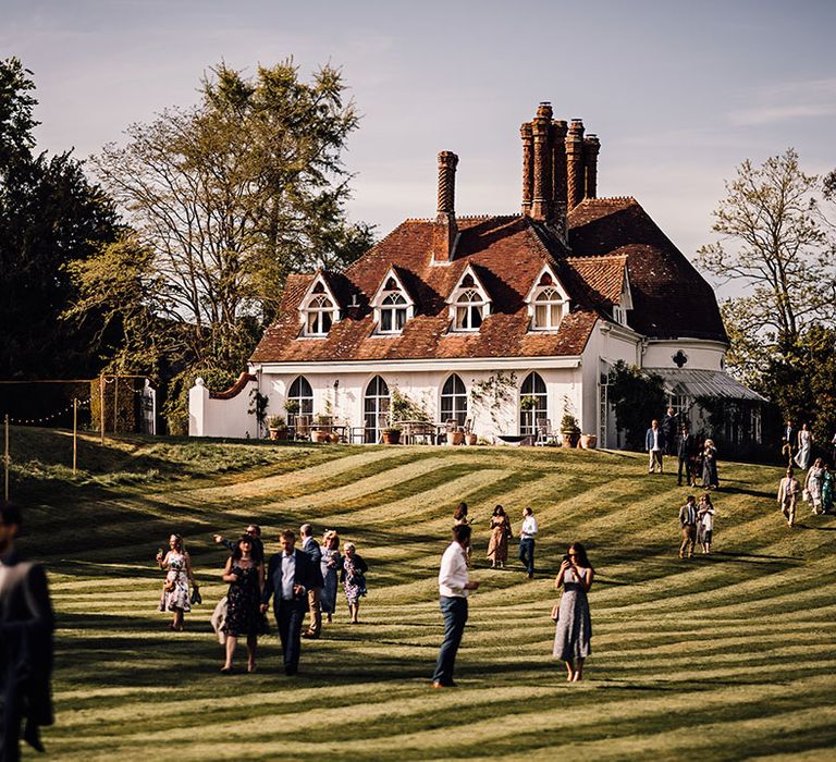 Wedding guests walk around and mingle at Houghton Lodge wedding venue 