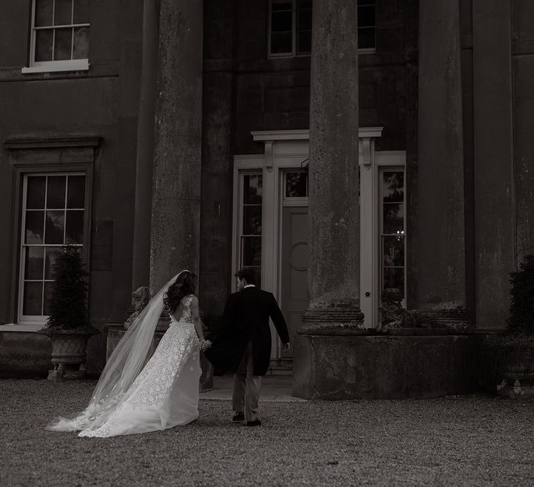 Bride in flower applique wedding dress with groom in morning suit outside their wedding venue 