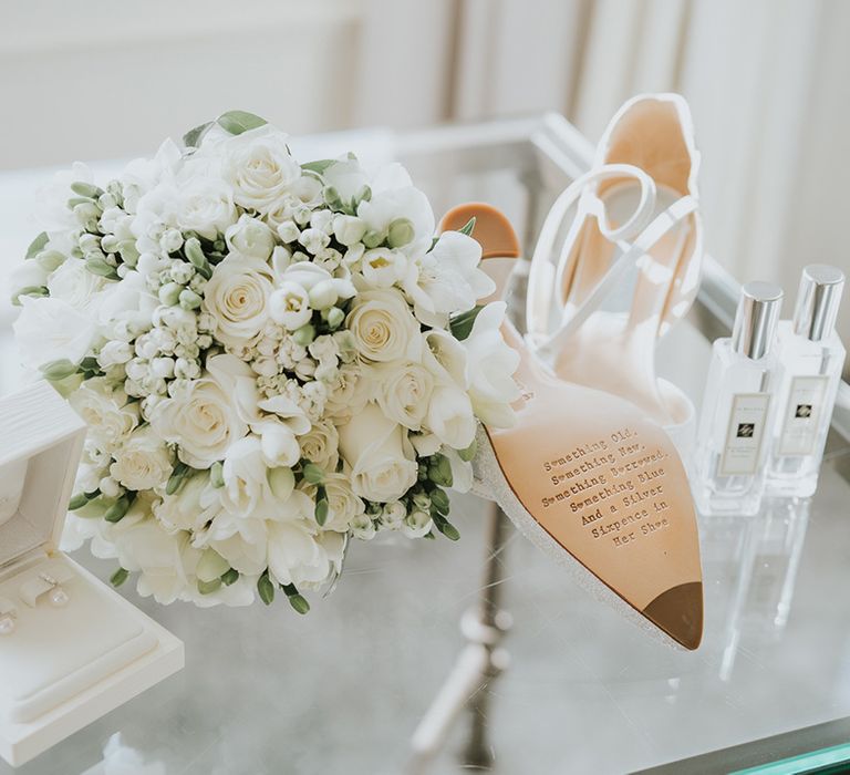 Pearl earrings with white flower bridal bouquet, Jo Malone perfume and engraved white heeled wedding shoes 