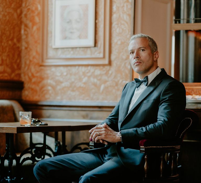 Groom seated in wooden chair at The Zetter Townhouse in black tie for registry city wedding 