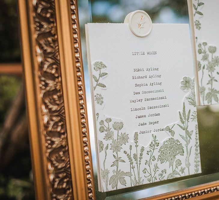 Table plan on gold framed mirror finished with white stationery, typewriter font and floral design