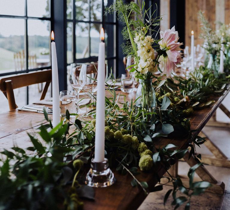 White taper candles with lots of foliage and pink and white flowers for the top table decoration 