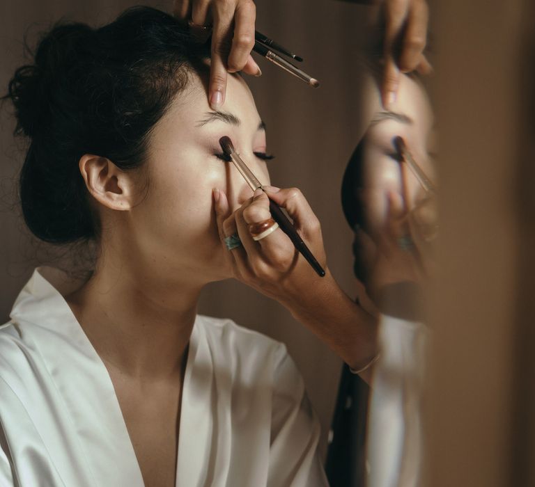 South East Asian bride has her eye makeup done on the morning of her wedding day 