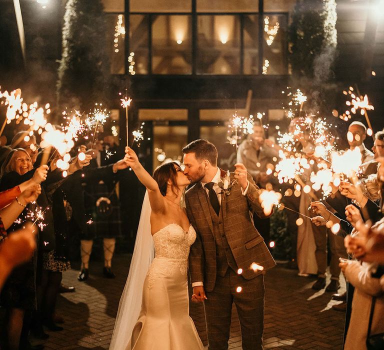 Bride and groom kiss at the end of their sparkler exit 