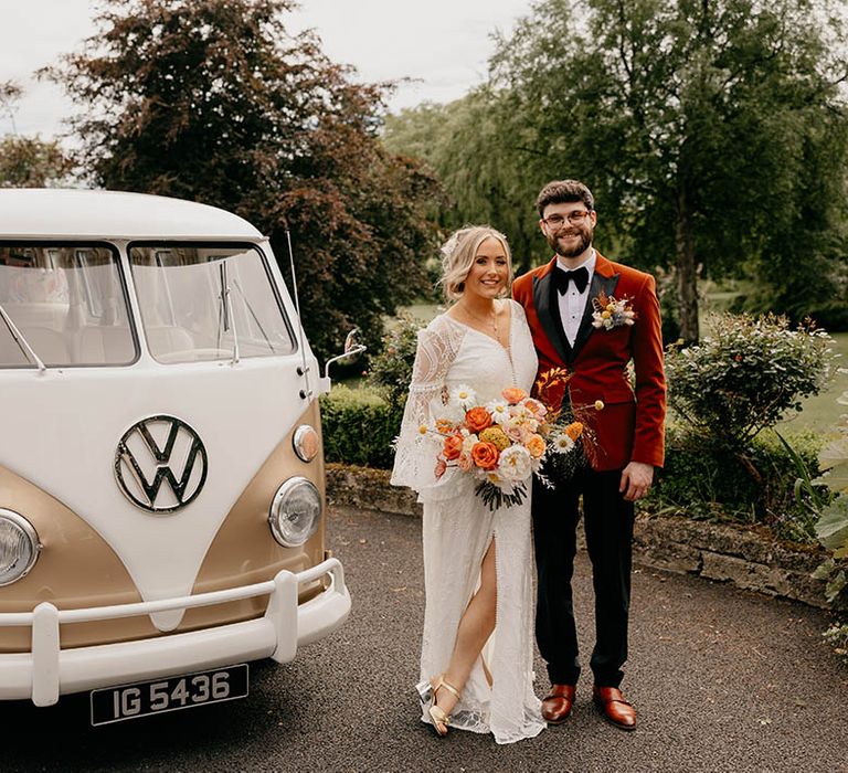 Bride and groom stand next to their cream and gold VW camper wedding transport 