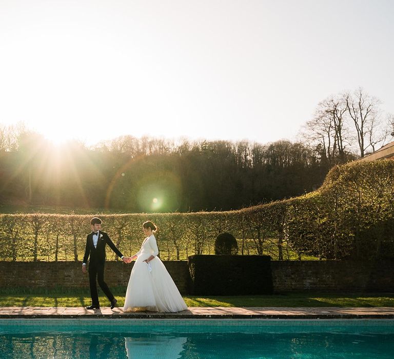 Bride & groom walk alongside the pool during golden hour at Findon Place 