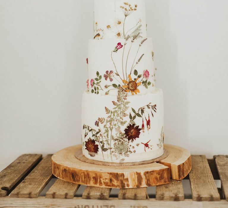 Three tier flower pressed wedding cake with a cake topper of a lego couple