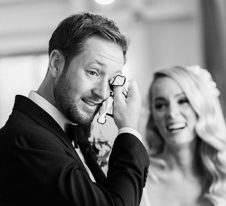 Groom wipes his eyes as he sees the bride for the first time on their wedding day 