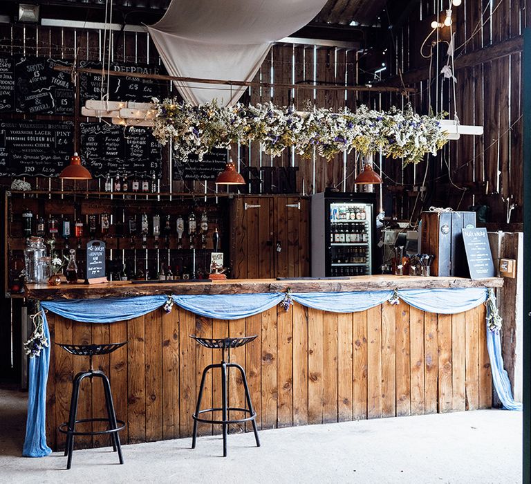 Rustic wedding bar decorated with pale blue fabric, dried flowers, and bunting 