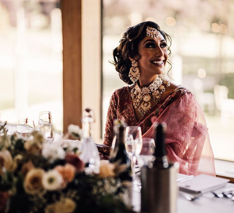 Indian bride wears her dark hair in low curled up-do 