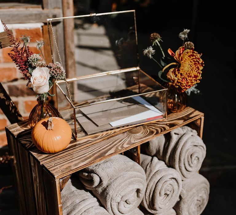 Glass box full of guest cards on top of a wooden crate with grey blankets for the guests