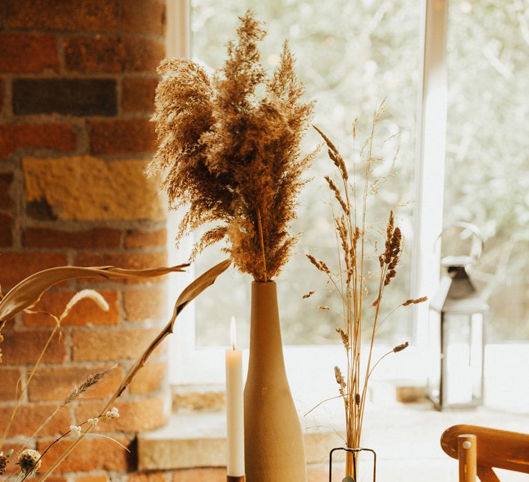 Pampas grass and boho styled table with brass candle holders and neutral toned table runner 