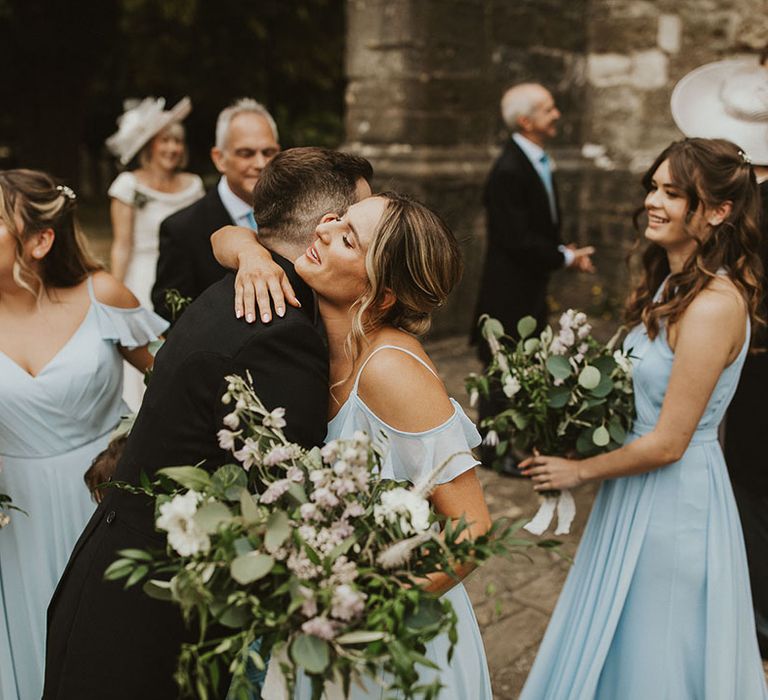 Bridesmaids in pale blue dress congratulate the bride and groom on their marriage 