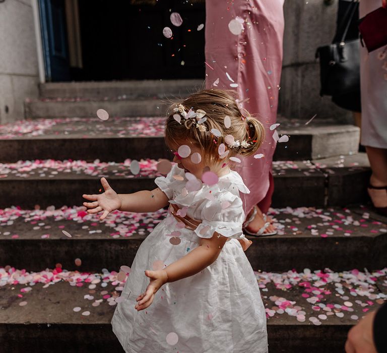 Young flower girl in short sleeve white dress dancing in the pink confetti at Somerset House